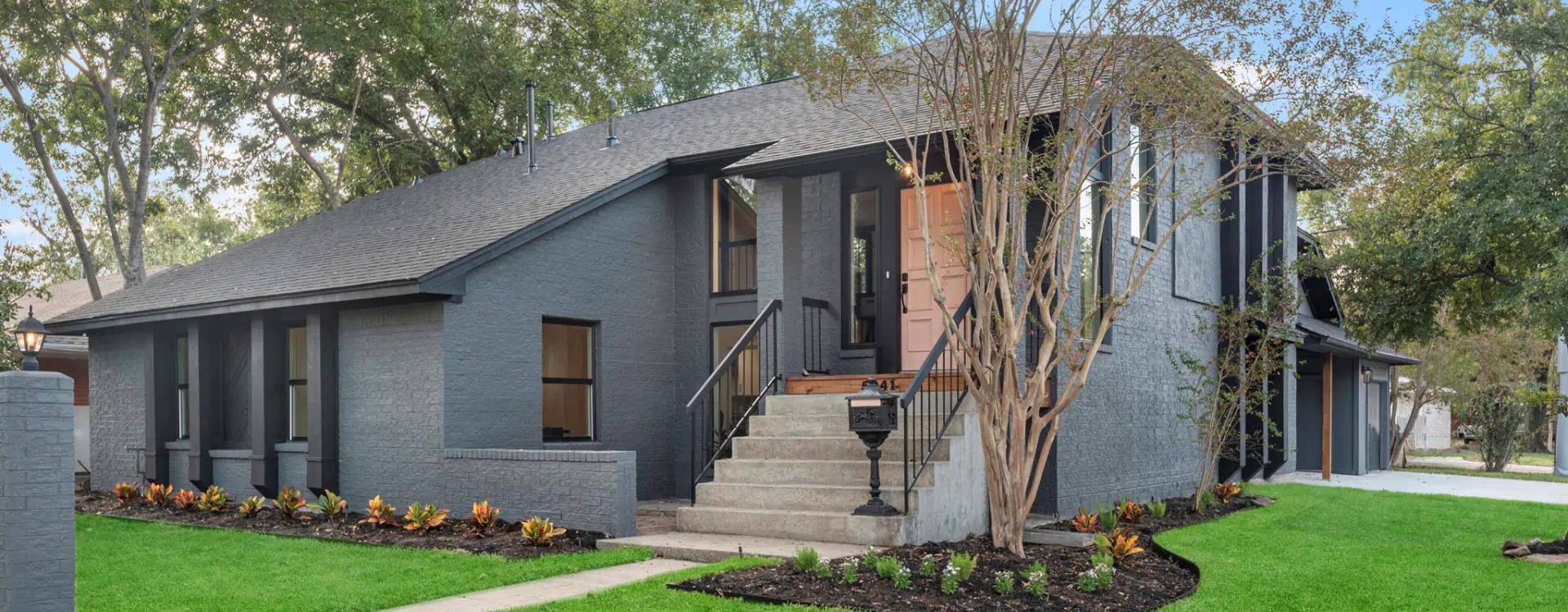 grey house with a dark grey roofing and patio around