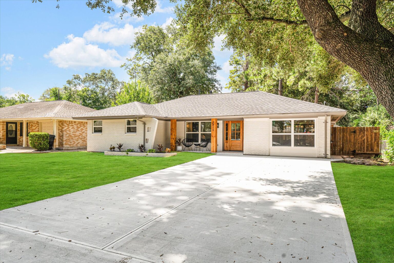 Light colored home with a large tree and 2 bright columns